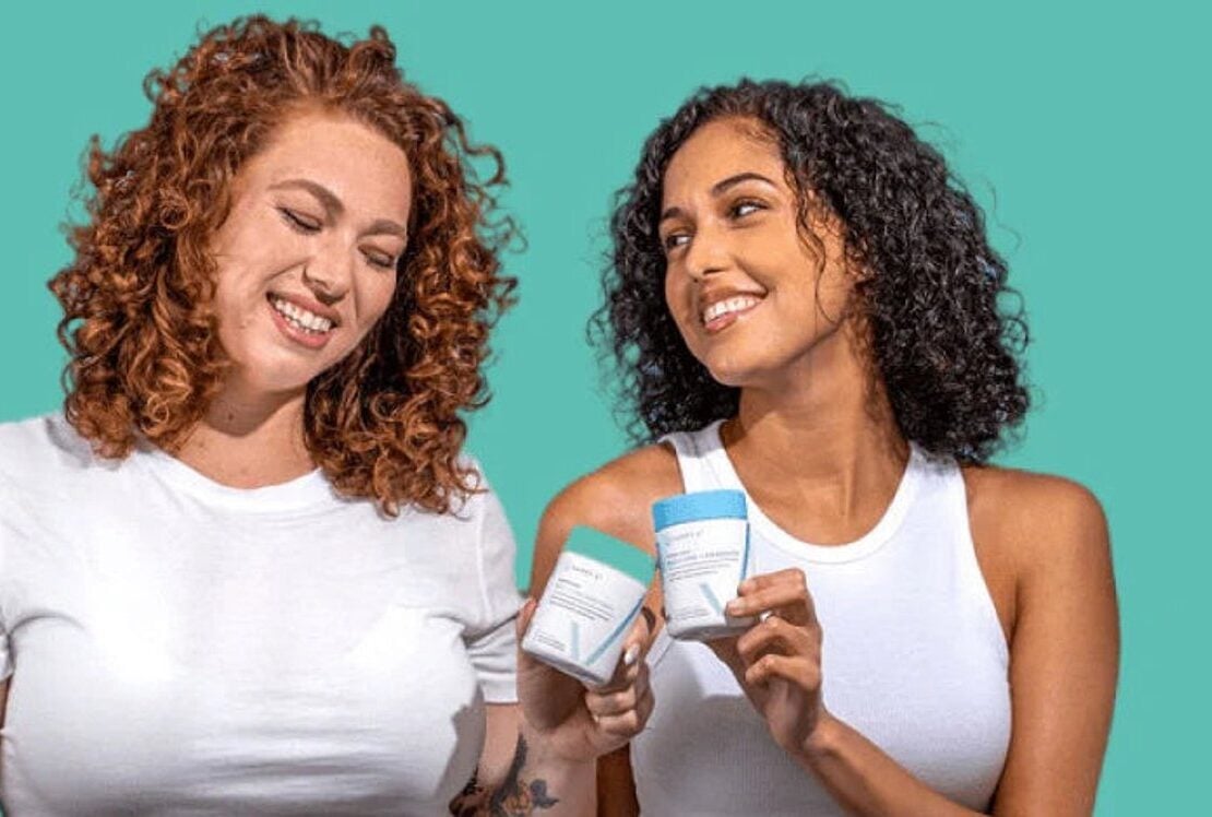 Two women holding Happy V wellness products in a bright lifestyle scene