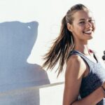 Lächelnde Frau mit Wasserflasche als Symbol für gesunde Ernährung