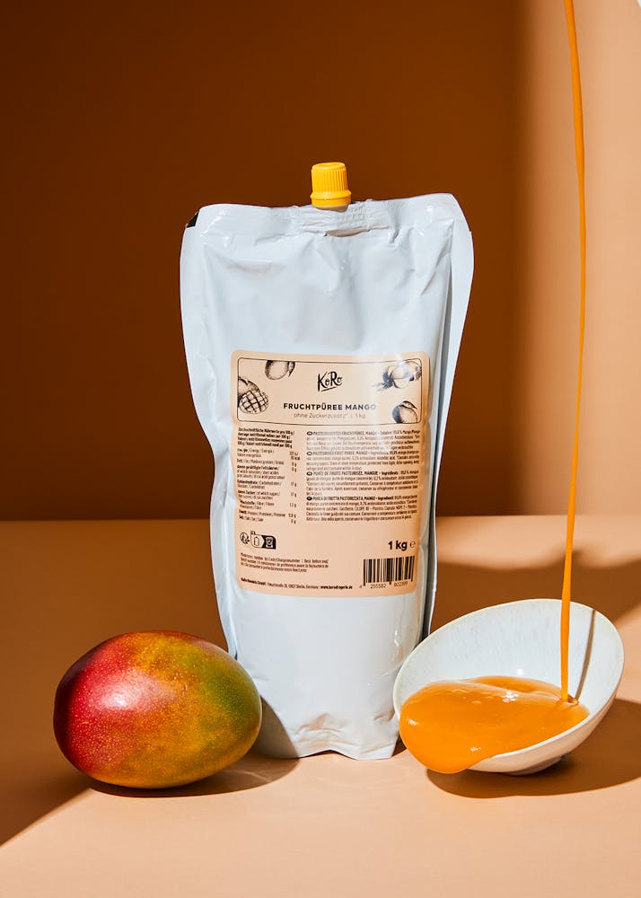 Beutel Fruchtpüree Mango 1 kg neben einer Mango