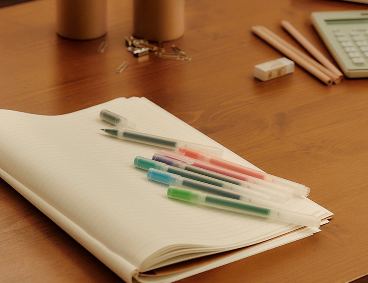 MUJI stationery arranged on a wooden desk