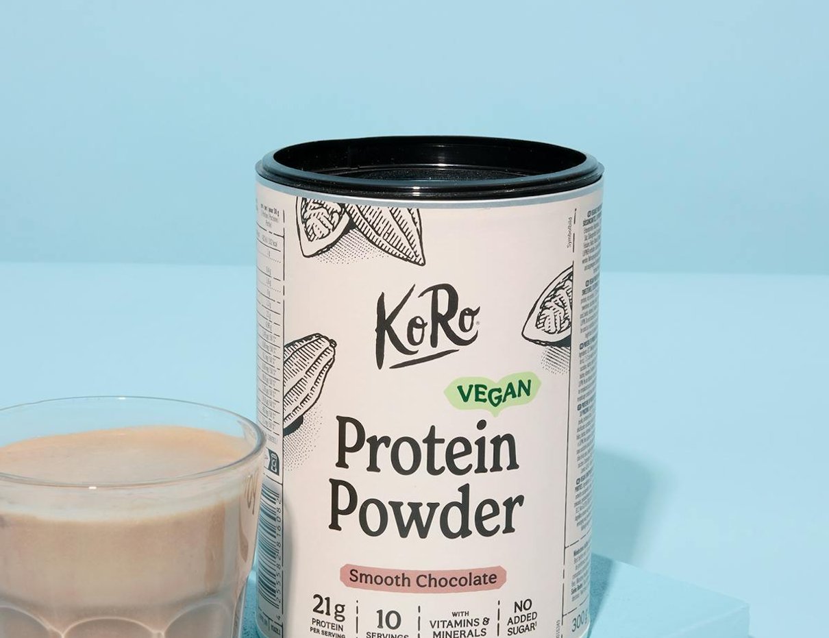 Packung Vegan Protein Powder Smooth Chocolate von Korodrogerie neben einem Glas