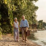 Mature couple walking beside a river with a picnic basket