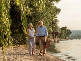 Mature couple walking beside a river with a picnic basket