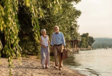 Mature couple walking beside a river with a picnic basket