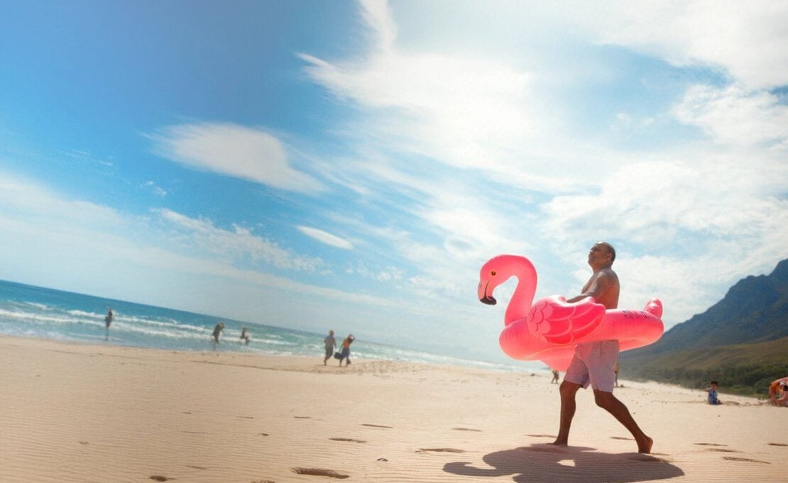 Travellers beside a bright coastal scene with a flamingo