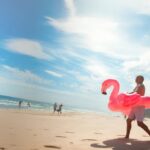Travellers beside a bright coastal scene with a flamingo