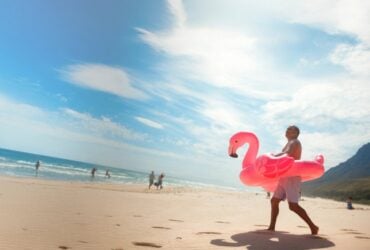 Travellers beside a bright coastal scene with a flamingo