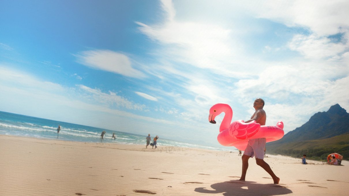 Travellers beside a bright coastal scene with a flamingo