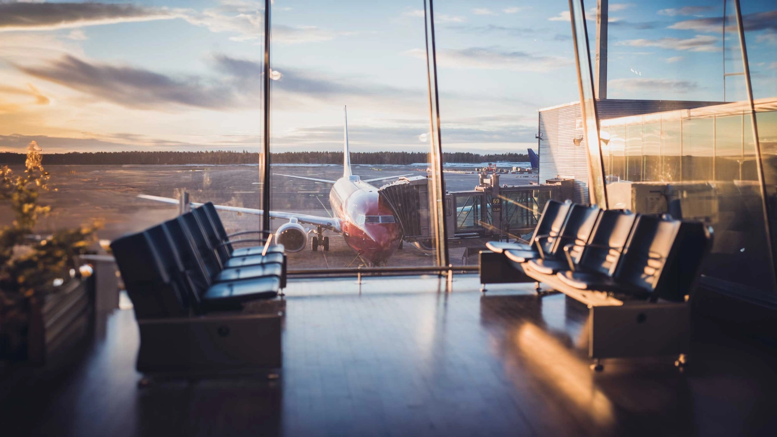 Airplane at an airport gate behind terminal windows